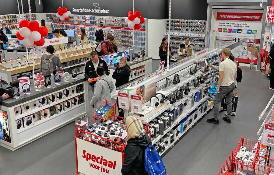 Customers browsing electronics in a busy European retail store